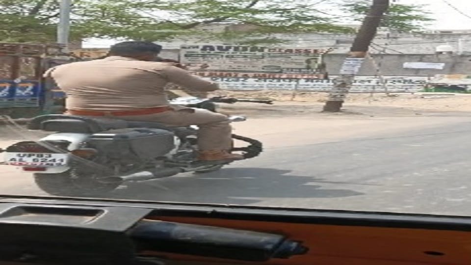 Policeman riding bike without helmet while talking on mobile