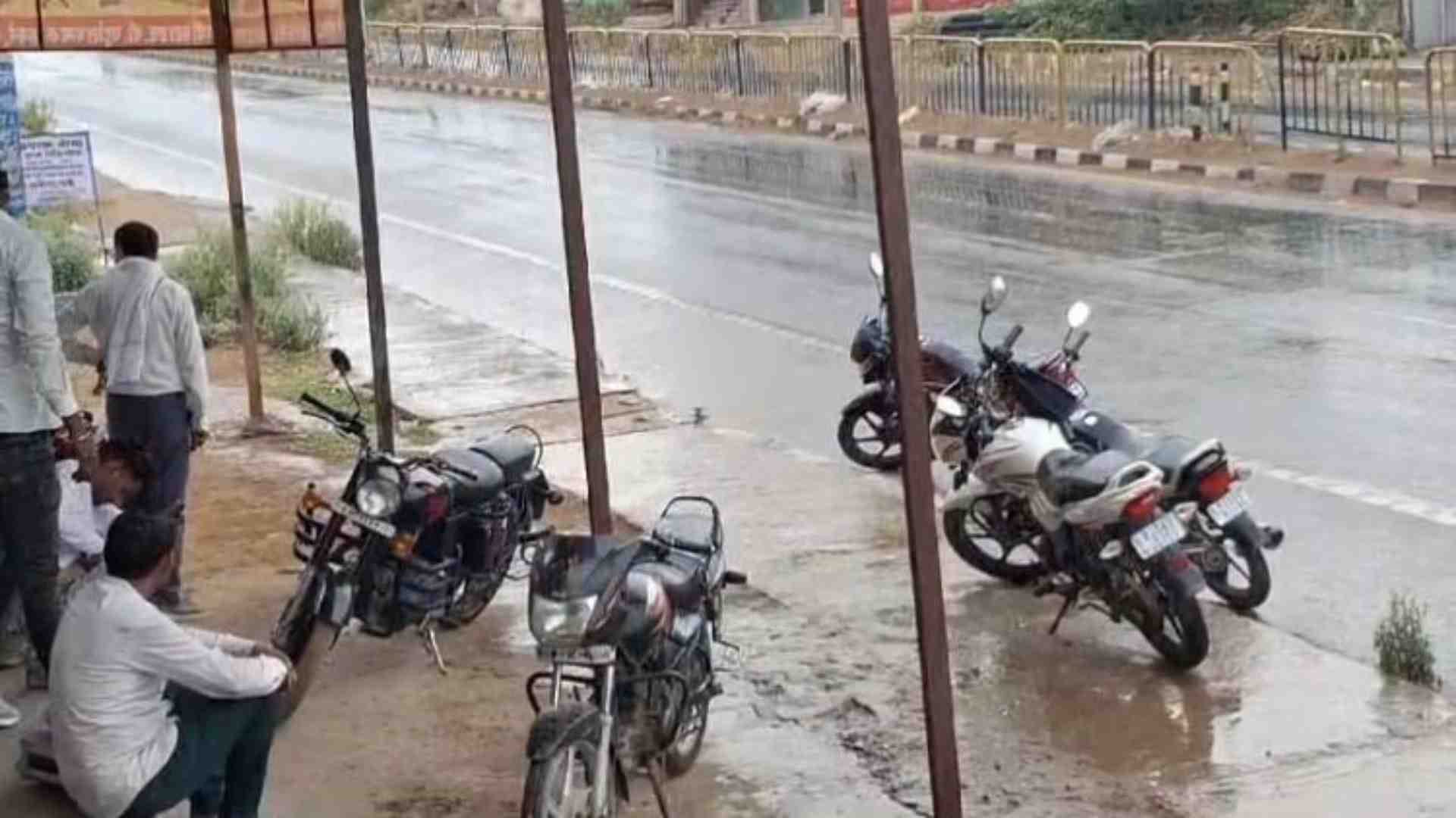 भीगने के डर से बारिश रुकने का इंतजार करते लोग।