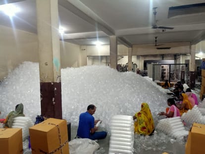 फैक्टरी में प्लास्टिक के ग्लास बनाते लोग
