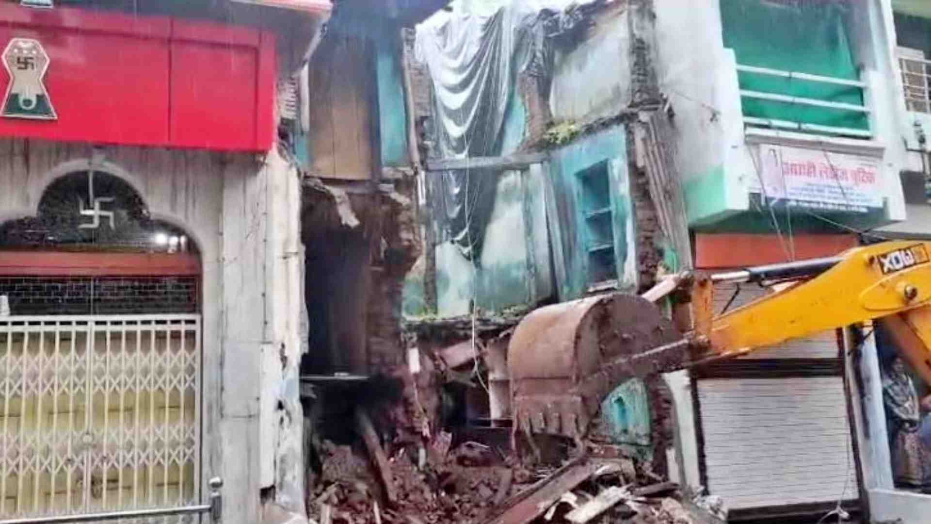मकान का मलबा हटाती जेसीबी।