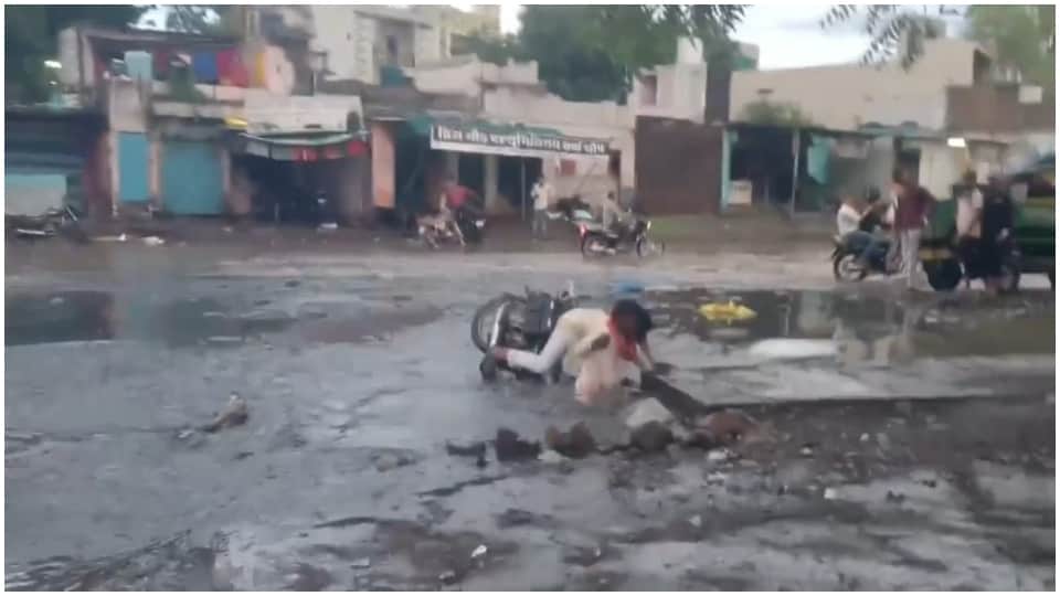गड्ढे में गिरे बाइक सवार।
