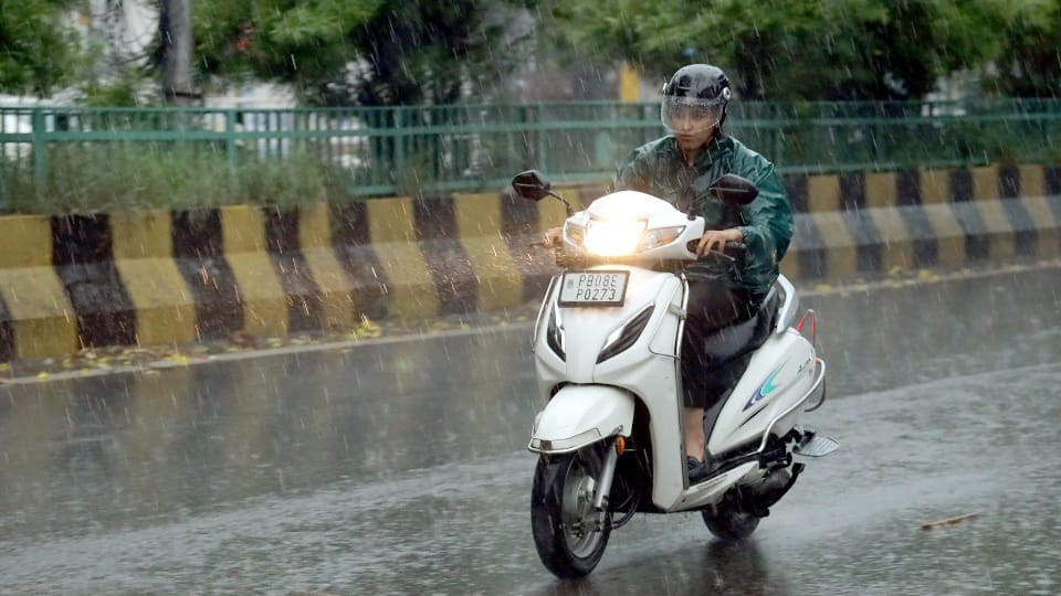 जालंधर में बारिश के दौरान गुजरती स्कूटी सवार युवती।