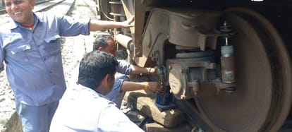 ट्रेन में पहिया ठीक करते कर्मचारी