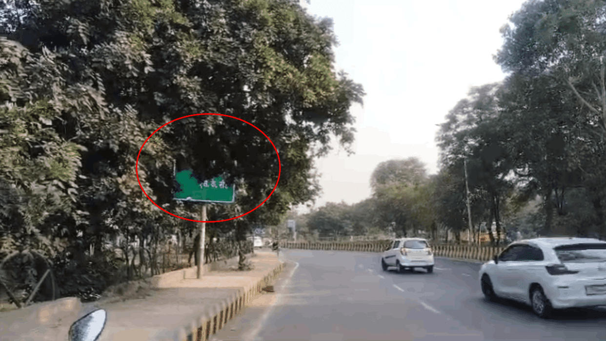 pedestrians are facing problems due to sign boards covered with tree branches In Greater Noida