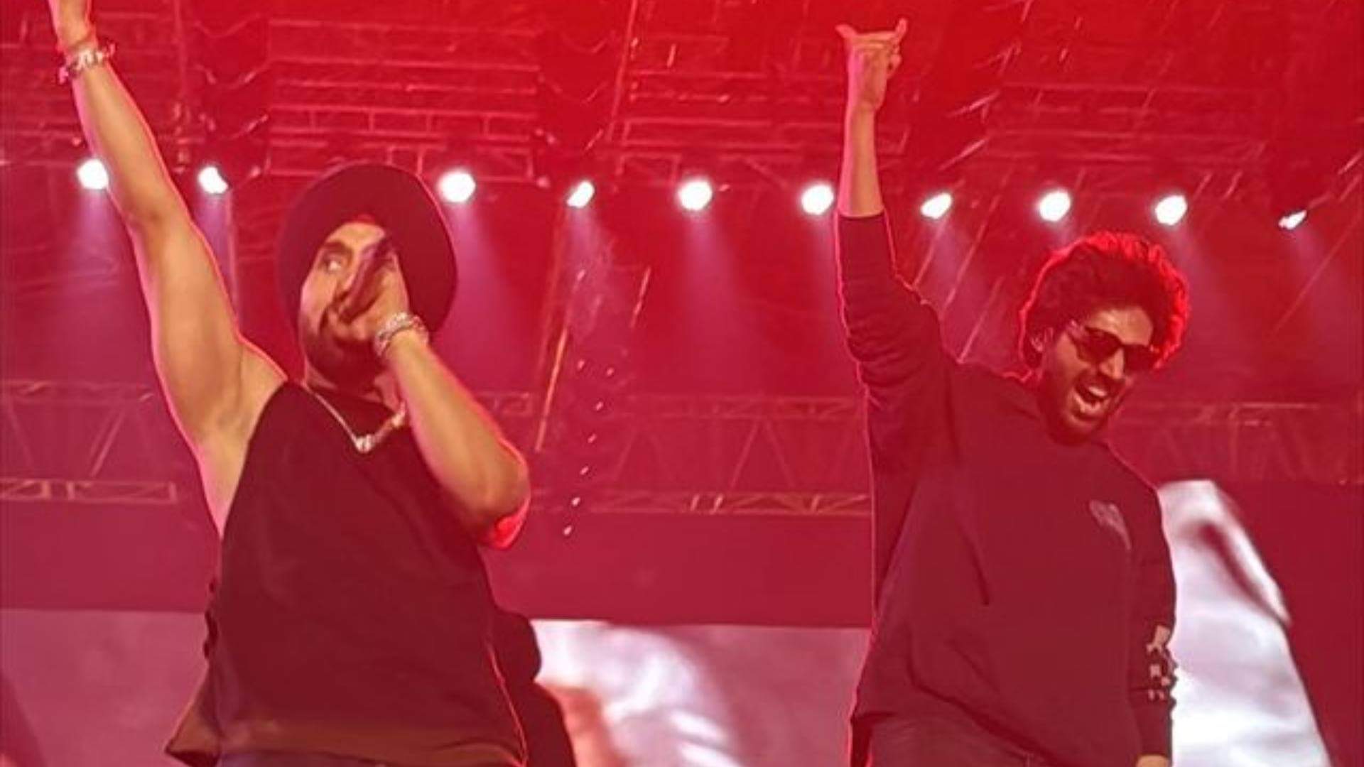 Diljit Dosanjh and Kartik Aaryan raising their hands as they twinned in black outfits at Ahmedabad show