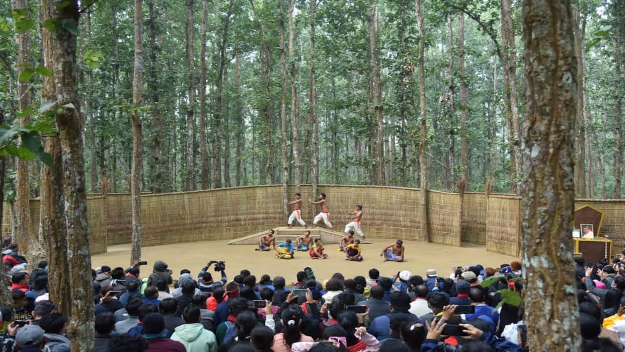Under the Sal Tree Theatre Festival: Open stage under the trees, audience sits on straw; see picture