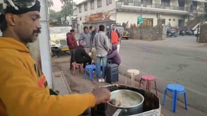 ठंड में चाय के स्टाल पर अलाव के पास बैठे लोग।