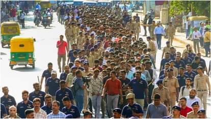 हिरासत में लिए गए अप्रवासियों को लेकर जाती पुलिस।