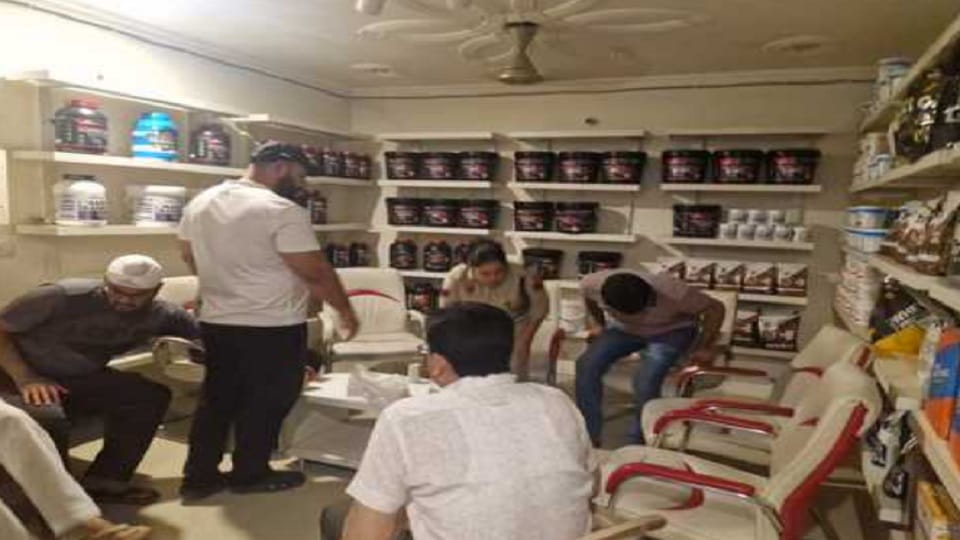 A young man aims a pistol at a worker in a shop in Narnaul