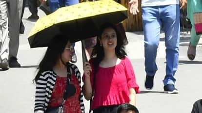 गर्मी में छाता लगाकर निकली युवतियां