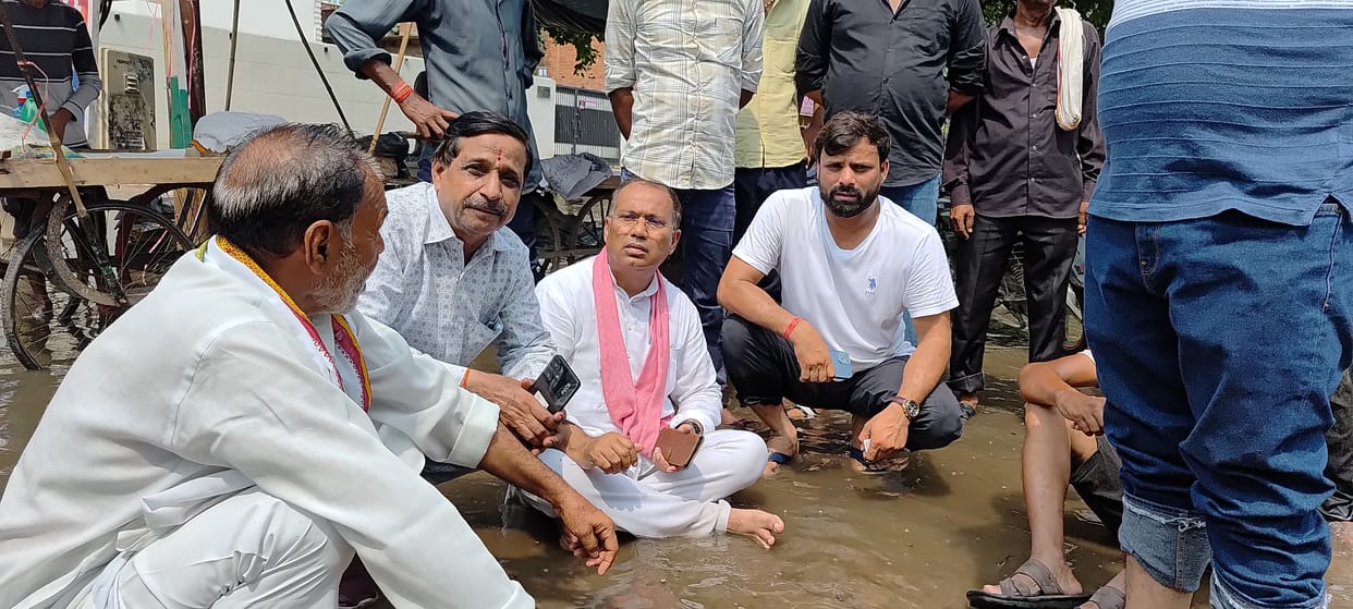 MLA sitting in dirty water filled on road