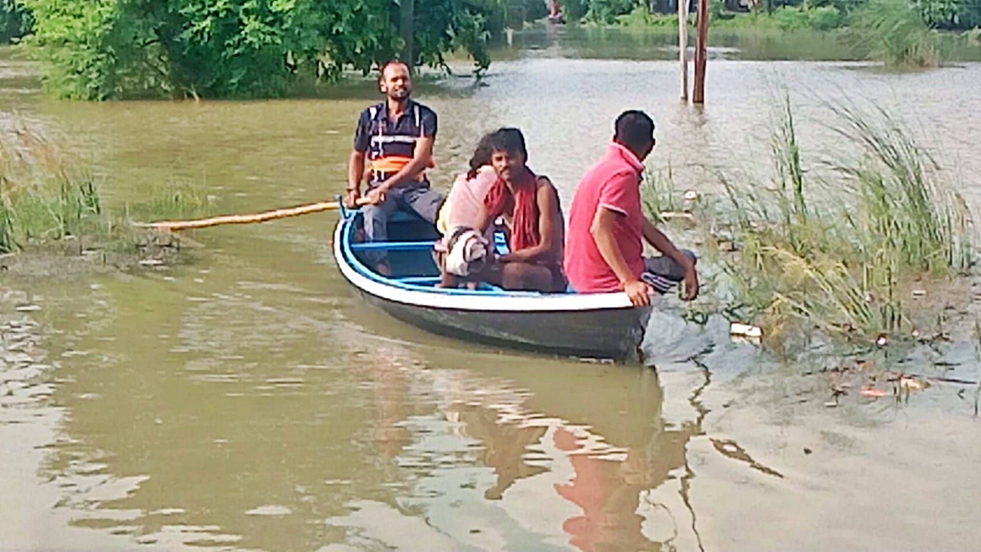 बाढ़ के पानी में नाव का सहारा लेते ग्रामीण