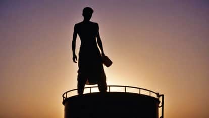 Fed up with encroachment-dirty water in street youth climbed on water tank with bottle of flammable substance