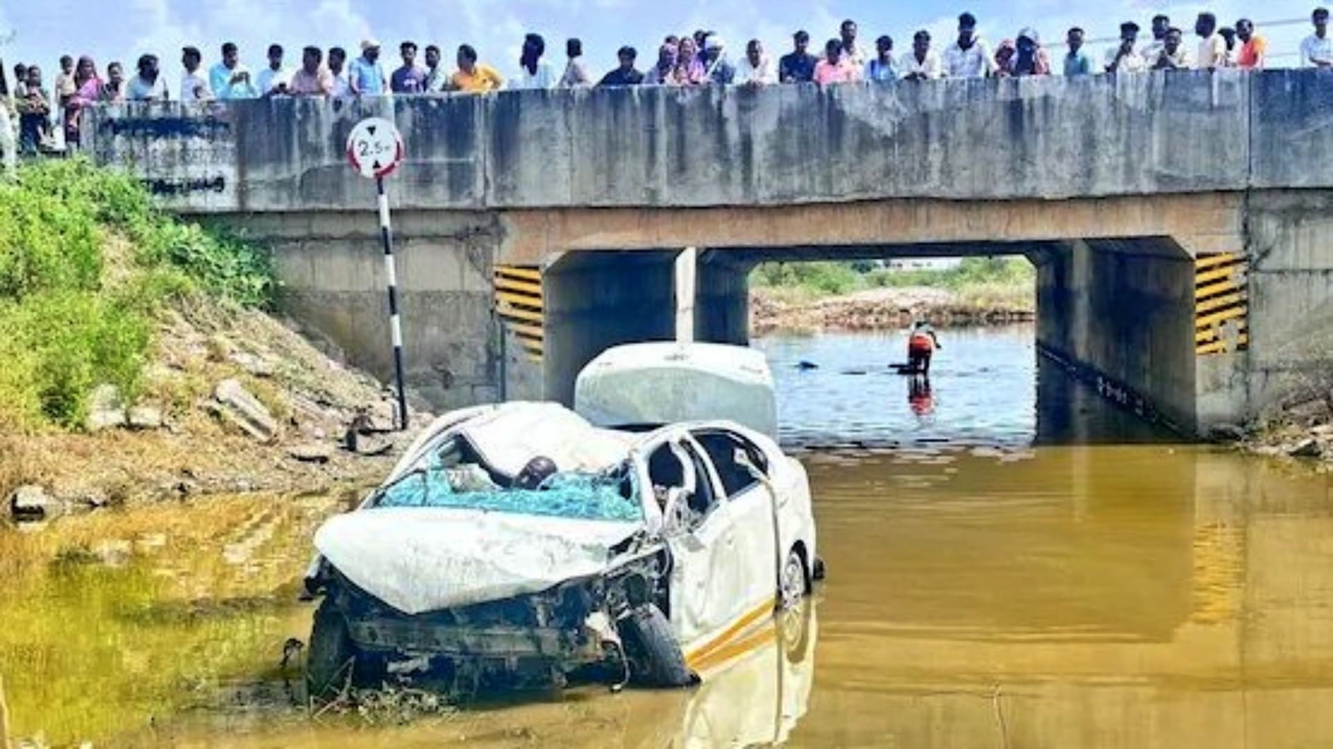 घटनास्थल पर क्षतिग्रस्त पड़ी कार तथा आसपास लोगों लगी भीड़