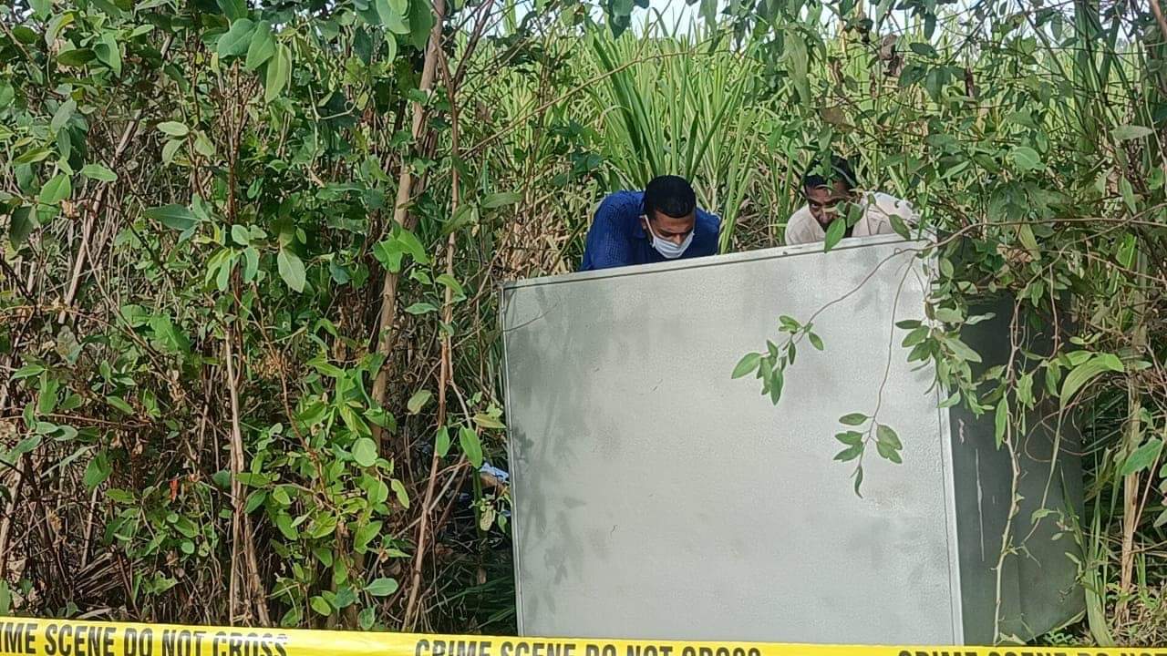 खेत में पड़ी तिजोरी की जांच करती पुलिस टीम