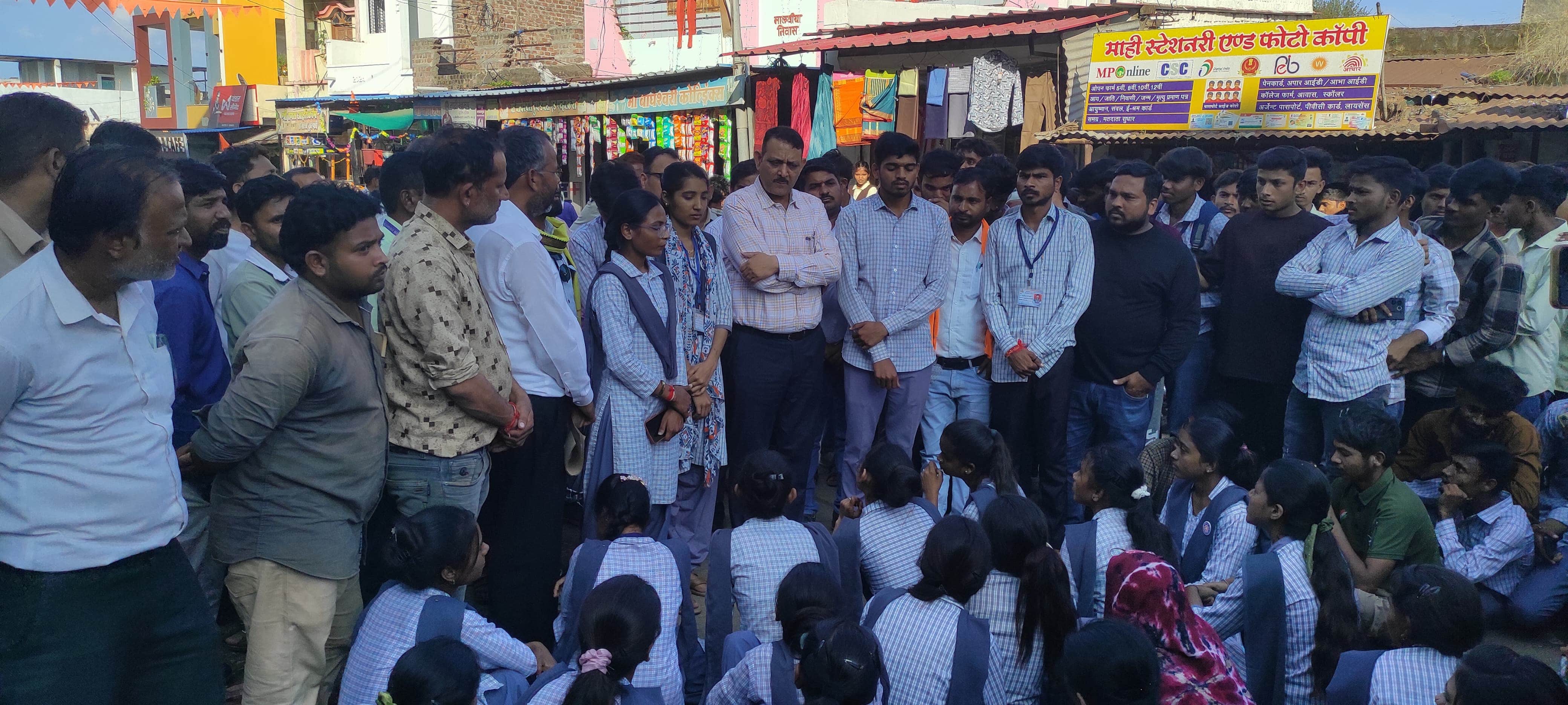 प्रदर्शन के दौरान का चित्र, एक समूह में छात्र-छात्राएं बात करते हुए।