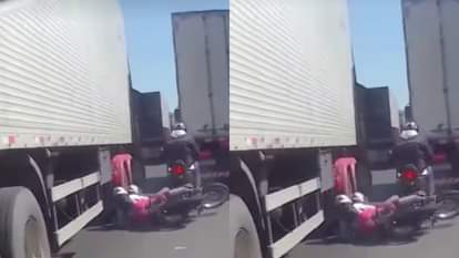 Biker tries to get out of traffic loses balance and woman narrowly escapes being run over by tyre