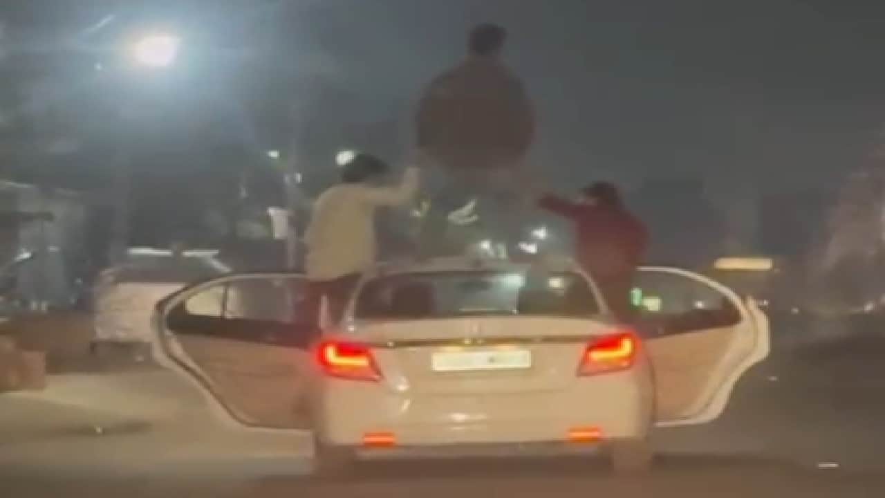 चलती कार पर स्टंट करते युवक