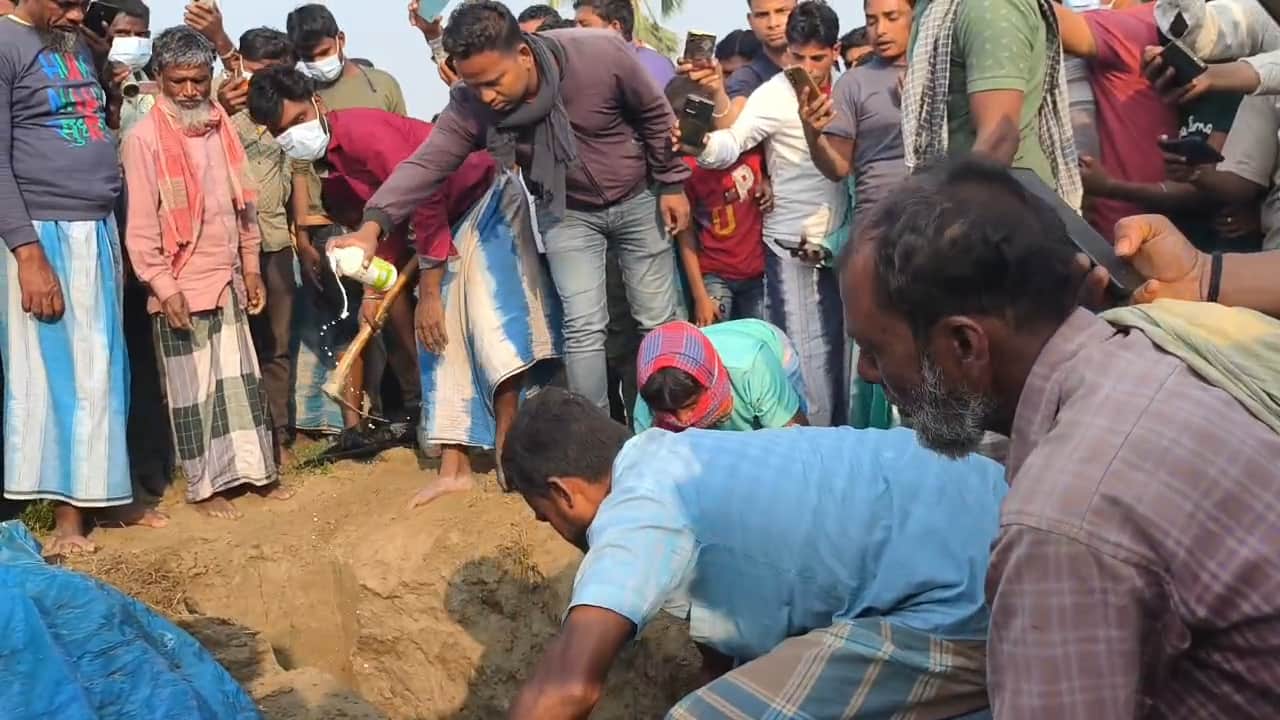 कब्र को खोदकर शव निकाले हुए लोग, मौके पर जुटी भीड़।