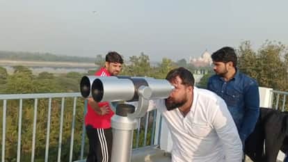 दूरबीन से इमारतों को देखते पर्यटक