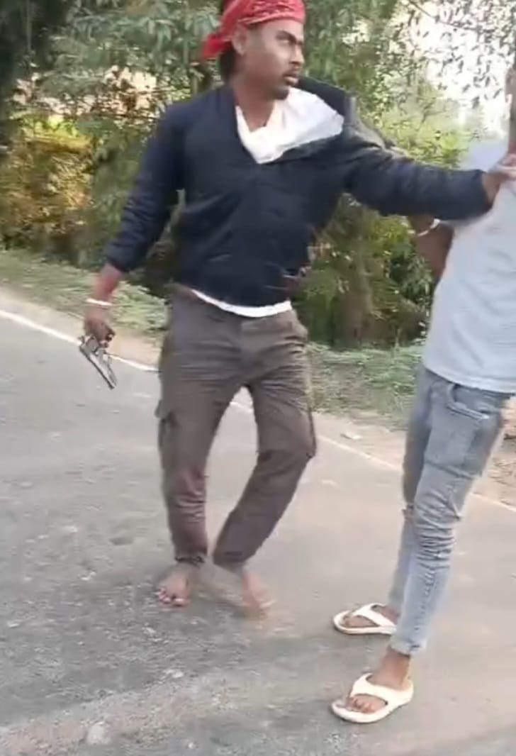 हाथ में पिस्टल लिए हुए आरोपी शख्स, एक अन्य युवक का कॉलर पकड़े हुए।