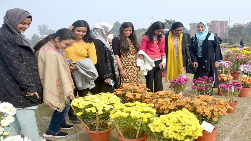 पुष्प प्रदर्शनी में फूलों देखती युवतियां