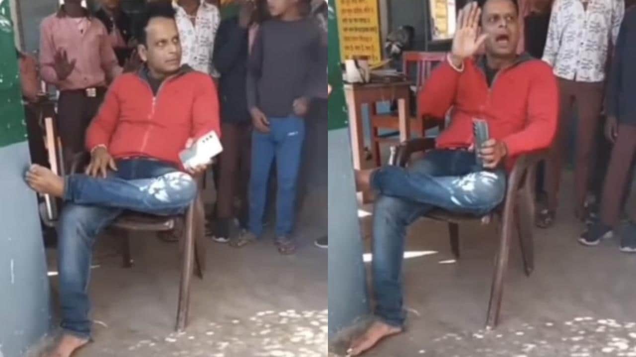 कुर्सी पर बैठा शिक्षक, पास में खड़े बच्चे व अभिभावक