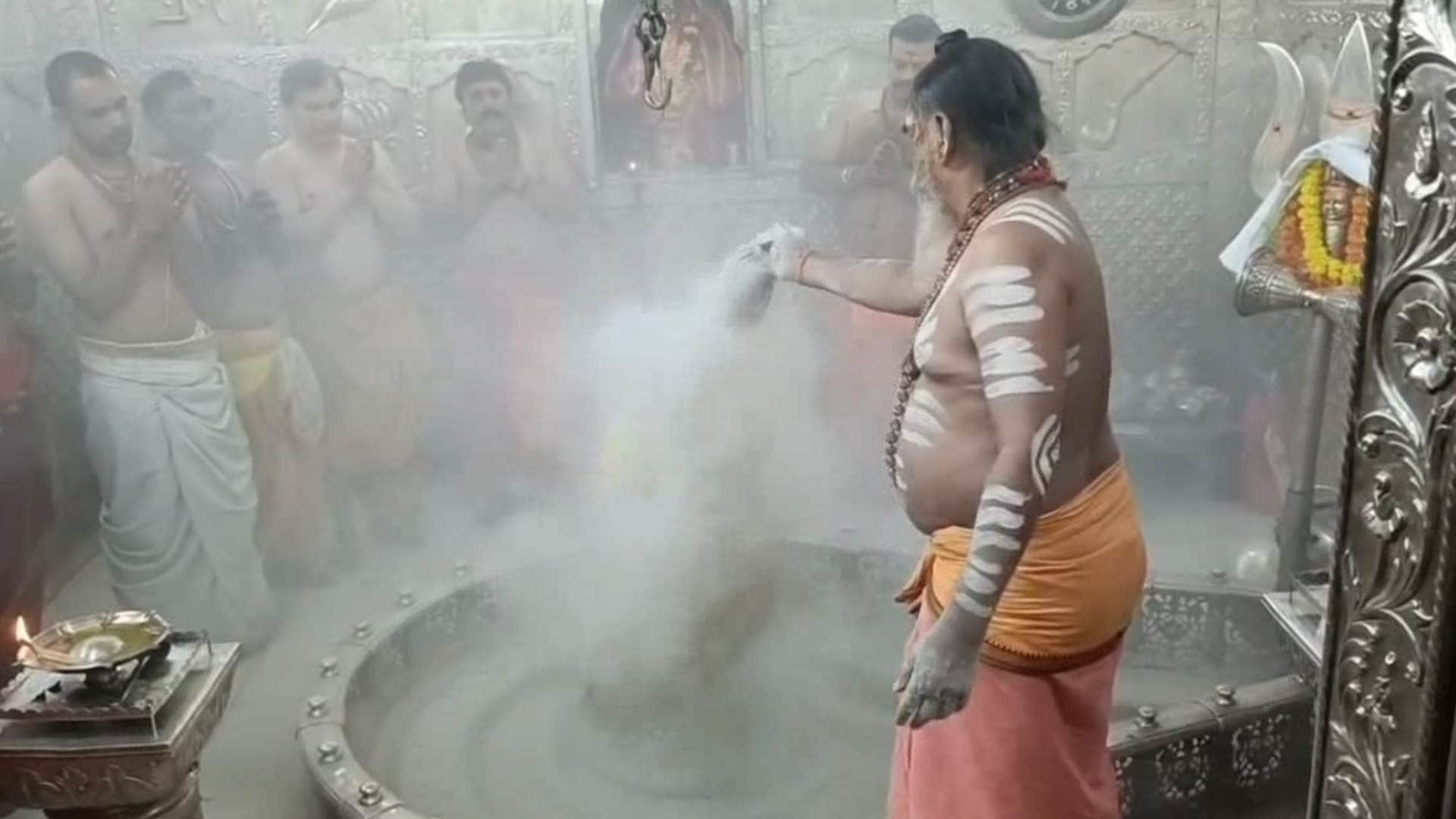 बाबा को भस्म रमाते पुजारी।