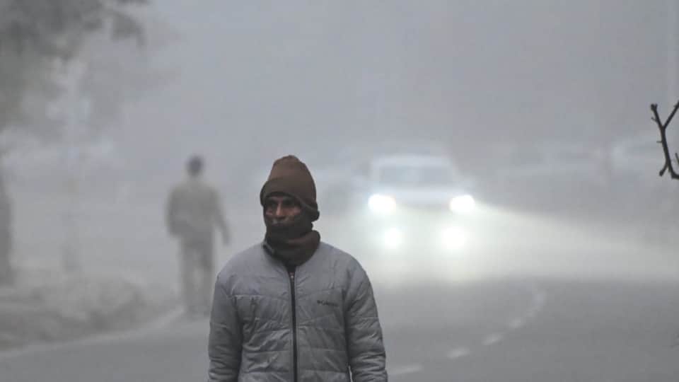 धुंध के बीच गुजरते राहगीर।