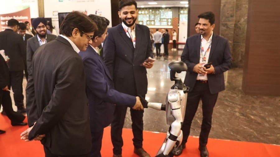 कार्यक्रम में एआई रोबोट से बात करते उद्यमी।