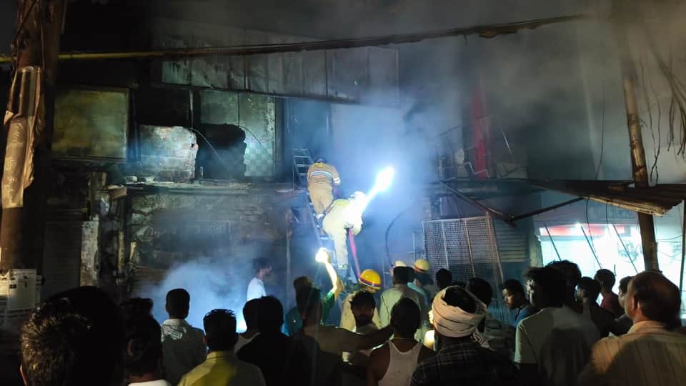 दुकानों में लगी आग पर काबू पाते दमकलकर्मी