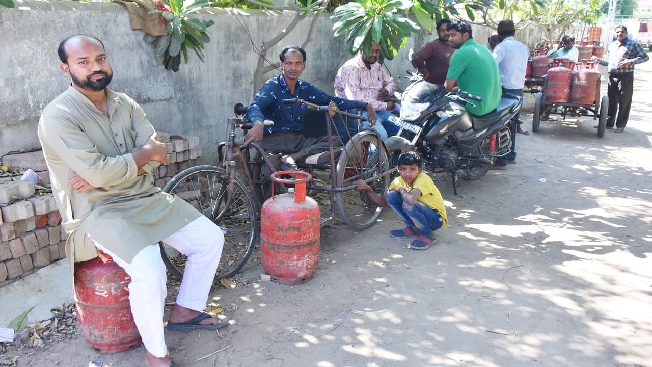 गैस सिलिंडर के इंतजार में बैठे लोग