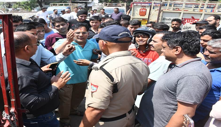 शीश महल स्थित इंडियन गैस  एजेंसी में आक्रोशित उपभोक्ताओं  को समझाता पुलिस कर्मी।