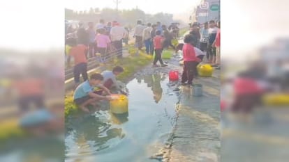 कौशाम्बी में सड़क पर गिरे डीजल को डिब्बे में भरकर ले जाते ग्रामीण।
