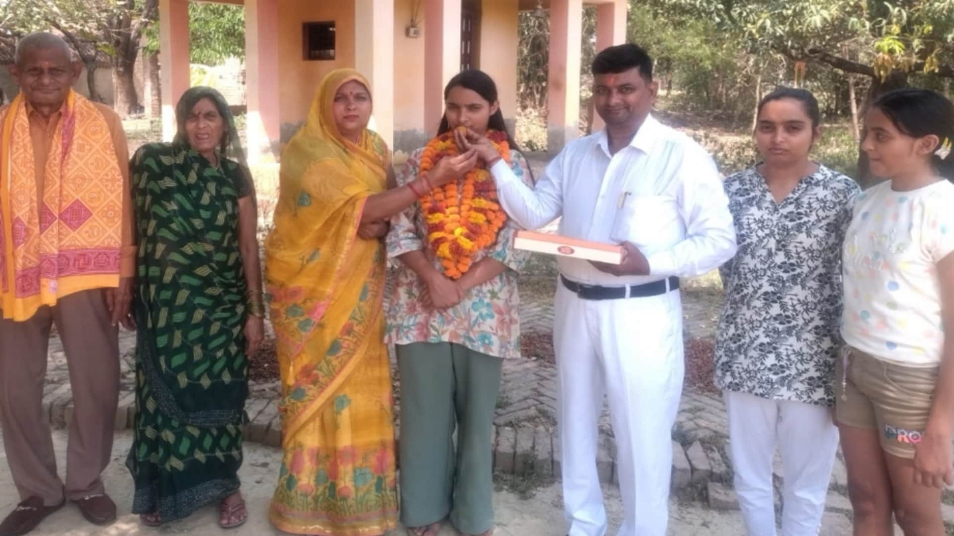 श्वेता द्विवेदी के एसडीएम बनने पर मिठाई खिलाते माता पिता साथ खड़े दादी दादा तथा बहनें।