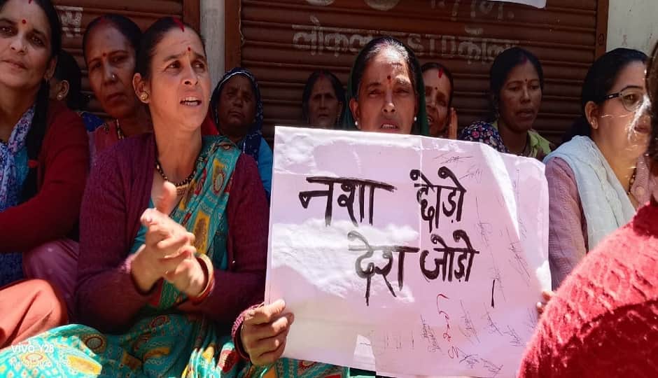 पोस्टर से शराब की दुकान का विरोध करती महिलाएं।