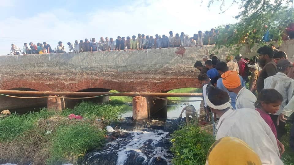 गंदे नाले में मिले शव को देखते ग्रामीण और पहुंची पुलिस