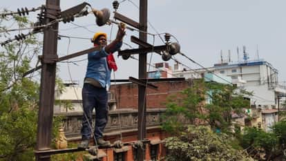 मंडुवाडीह में बिजली ठीक करता कर्मचारी।