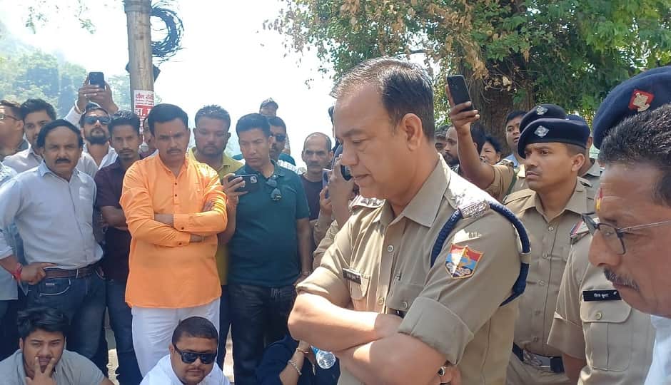 समुदाय विशेष की गिरफ्तारी की मांग पर जाम लगाए व्यापारियों और भाजपाइयों से बातचीत करते पुलिस अधिकारी