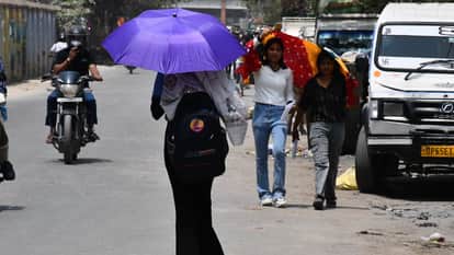 धूप से बचने को गमछा और छाता का सहारा लेतीं युवतियां।