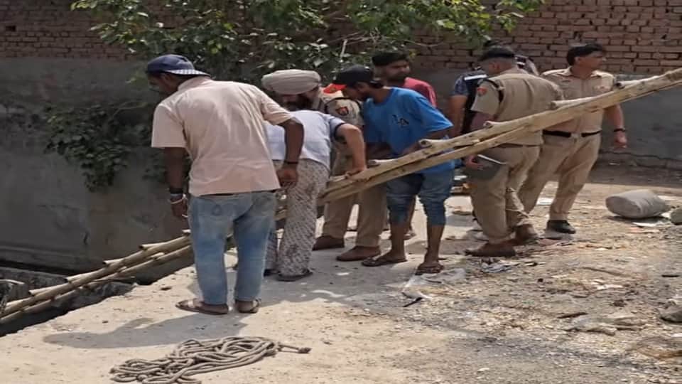 बच्ची का शव निकालते पुलिसकर्मी