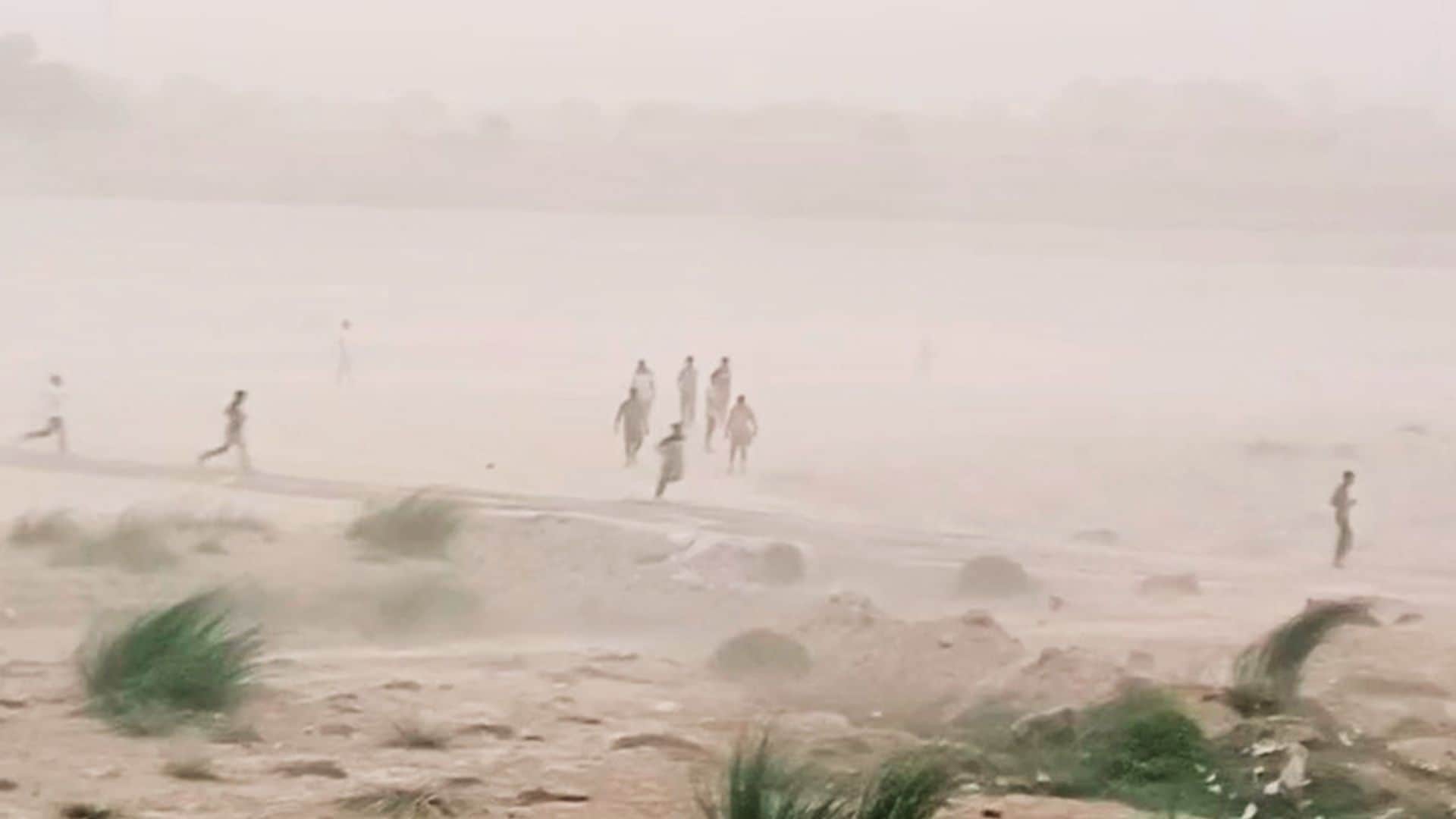 गंगा के उस पार रेती पर मस्ती करते लोग।