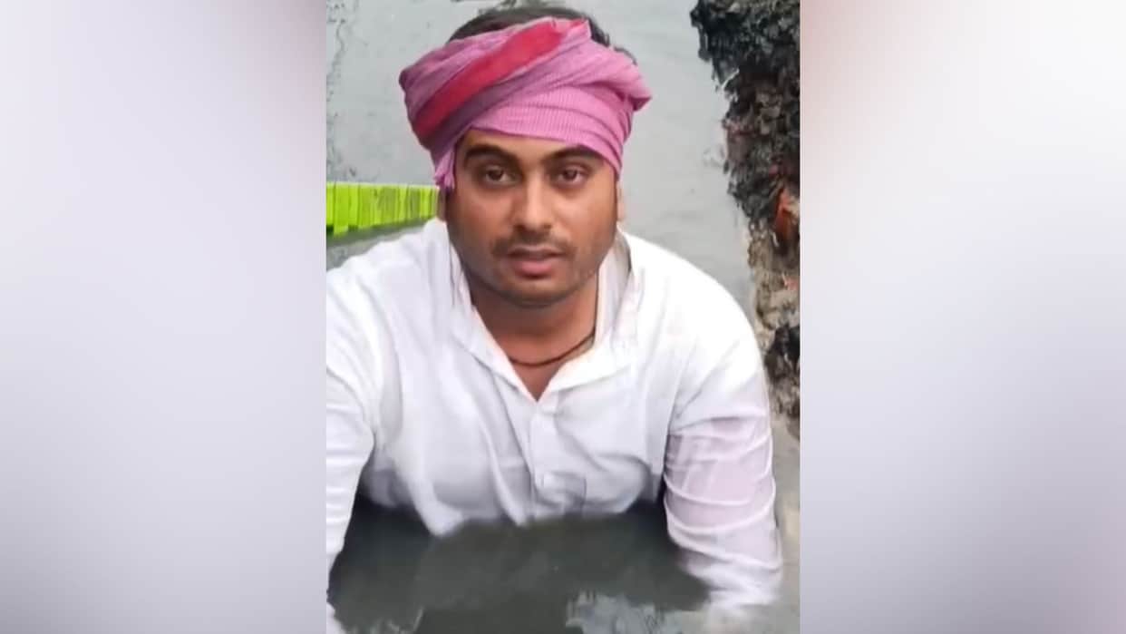 Young man sits on chair placed in drain stages unique protest demanding cleanliness in chandauli