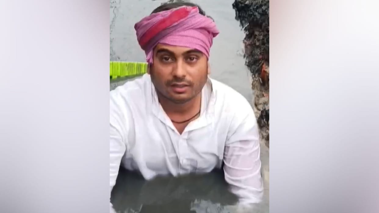 Young man sits on chair placed in drain stages unique protest demanding cleanliness in chandauli