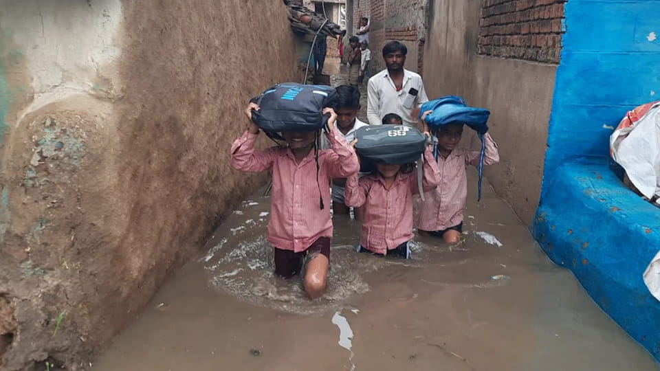 Children waded through waist-deep water with bags balanced on their heads