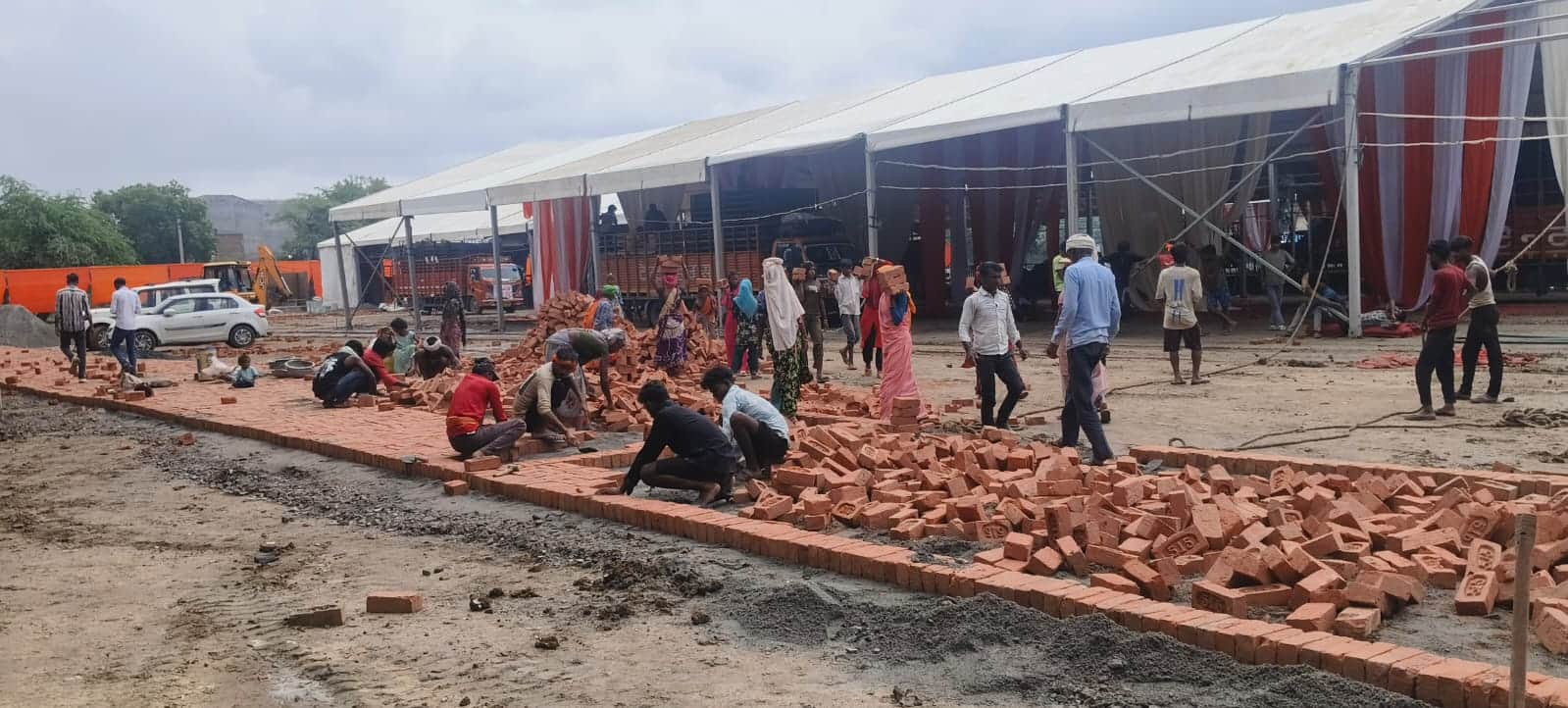 सभा स्थल पर ईंट लगाकर कीचड़ खत्म करते मजदूर