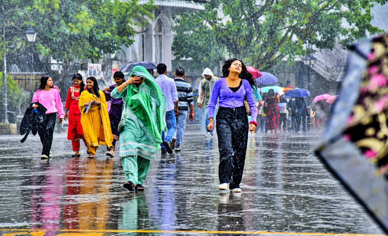 बारिश के दौरान रिज मैदान पर गुजरते लोग।