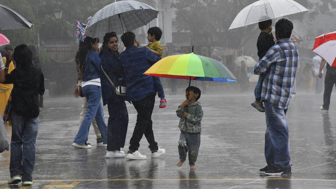शिमला के रिज मैदान पर शनिवार को हुई झमाझम बारिश के दौरान घूमते लोग।