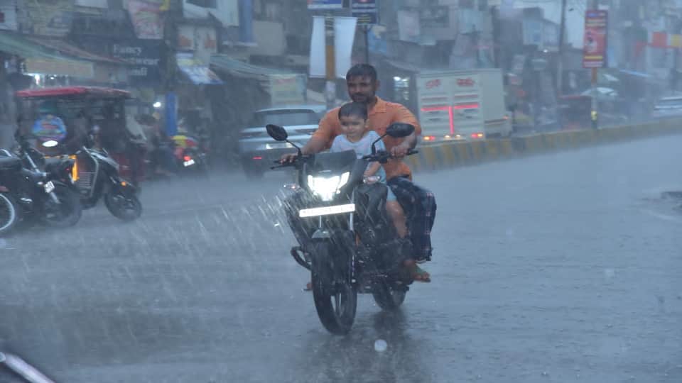 झमाझम बारिश के बीच गुजरता बाइक सवार।