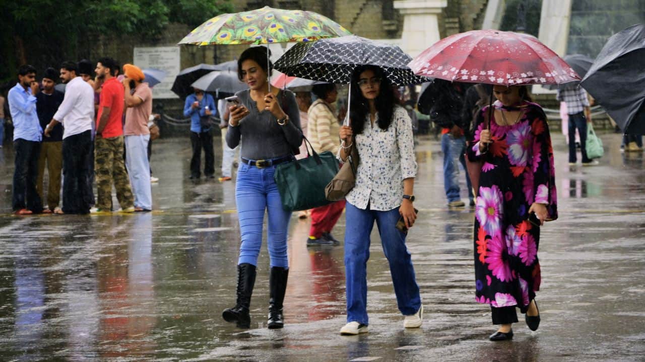बारिश के दौरान रिज मैदान पर गुजरते लोग।